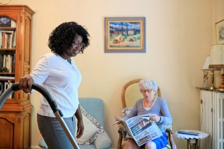 Une intervenante aide une dame âgée à entretenir son logement